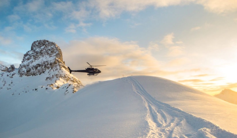 Helicopter approaching a snowy mountainside at sunset