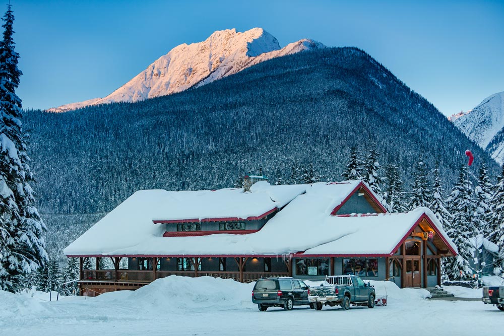 A snowy mountain lodge with against a mountain backdrop
