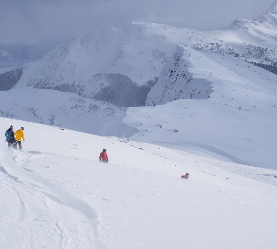 A group of skiiers make their way down a snowy mountain side