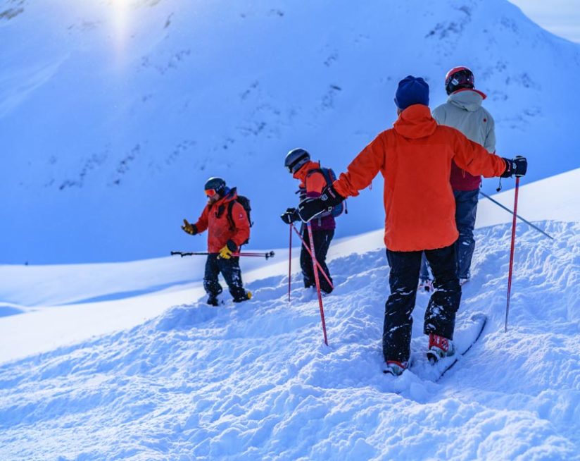 Four skiiers walking on a snowy mountainside