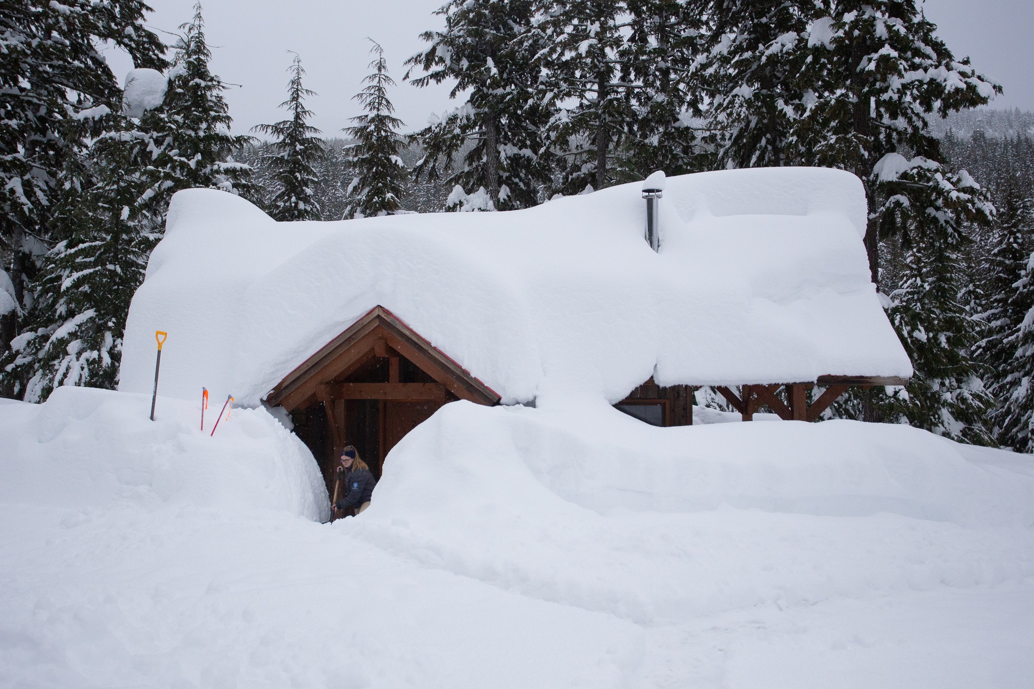 Deep december snow dump bc canada cabin, staff shovelling
