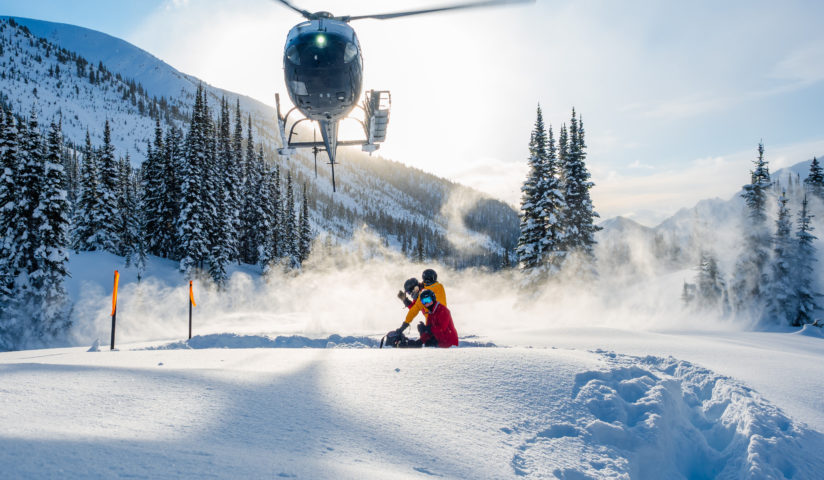 Helicopter coming down to pick up skiers for next run with sun shining down