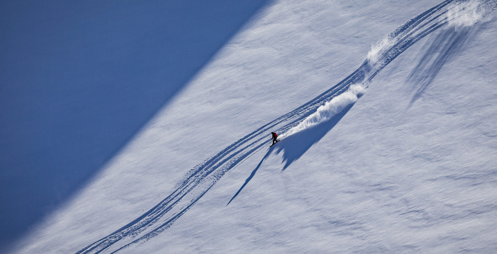 Snowboarder heliskiing powder in alpine terrain