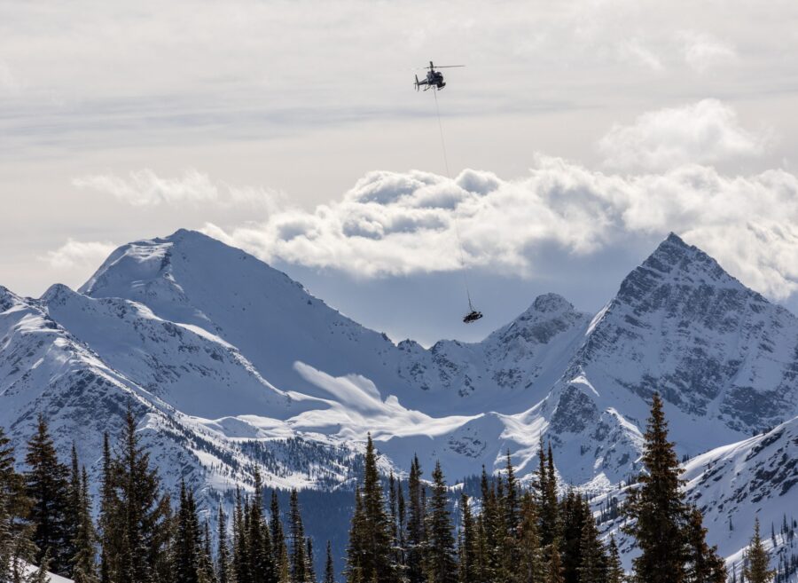 Helicopter flying while carrying snowmobiles at Great Canadian Heli-skiing.