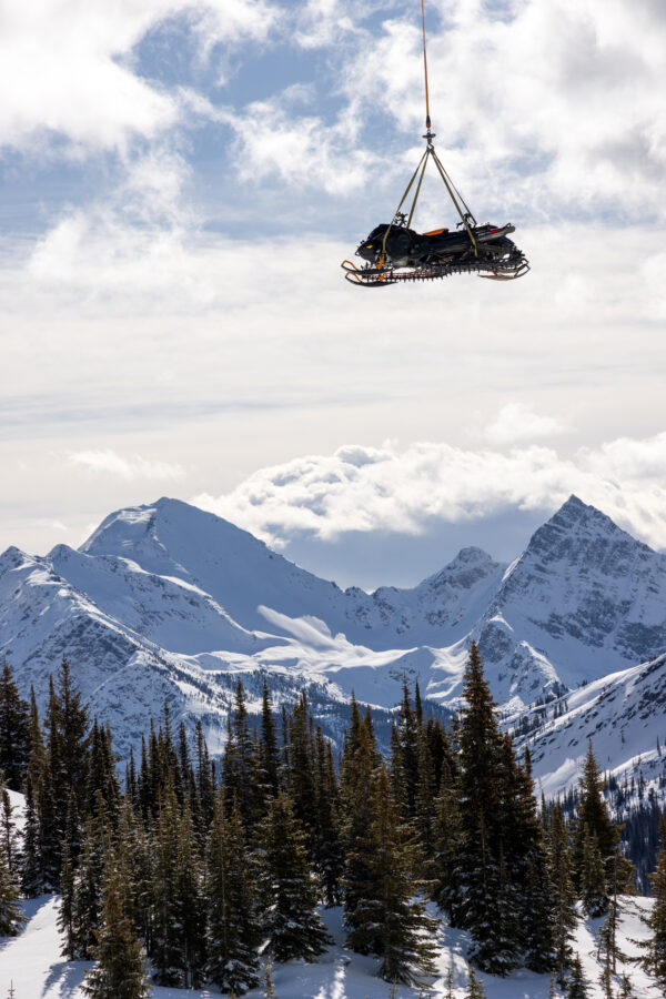 Sled being lowered by a helicopter for a snowmobile tour.