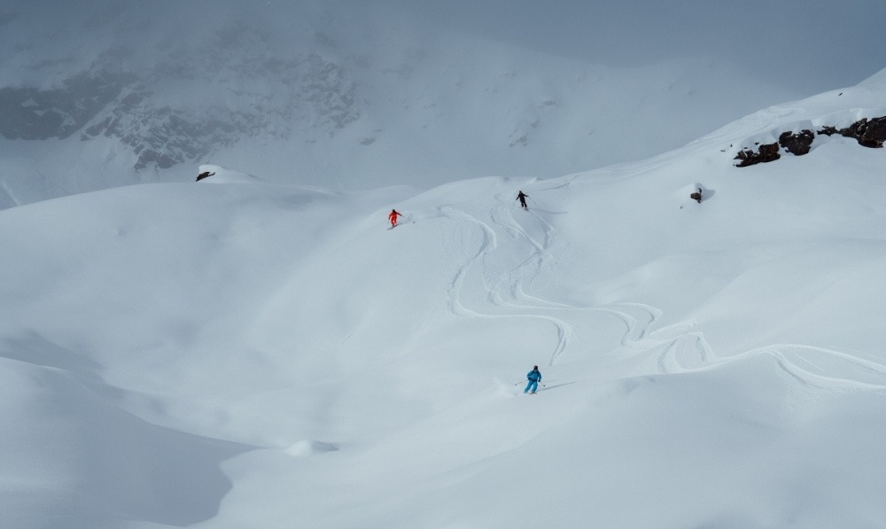 Three skiers making fresh tracks in deep powder in the Canadian backcountry