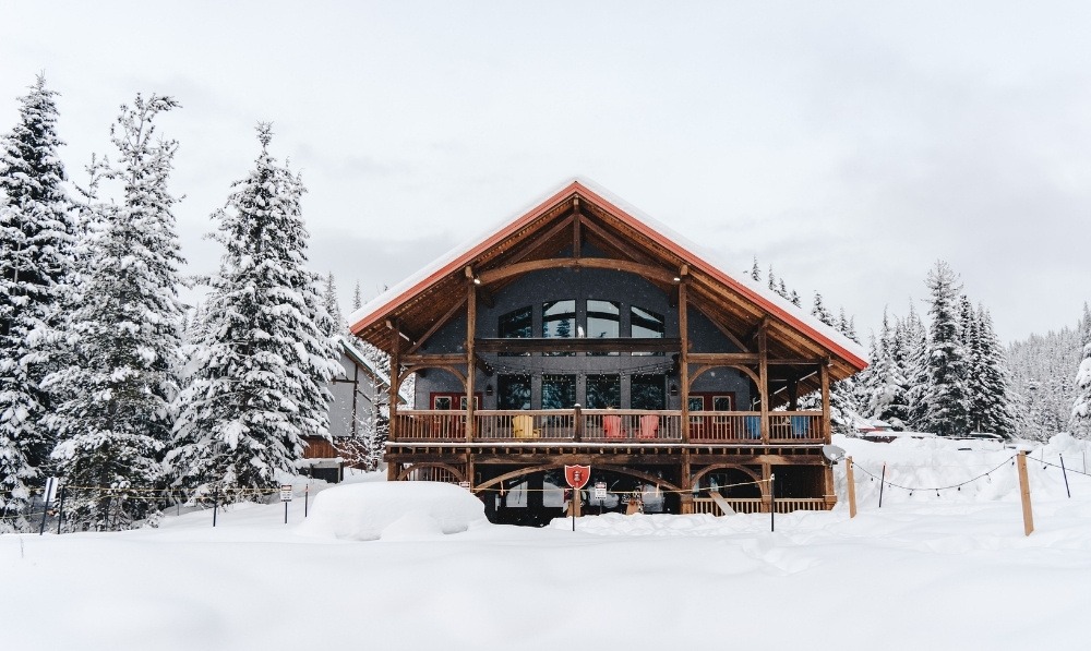 Front view of Heather Mountain Lodge surrounded by snow-covered trees in British Columbia